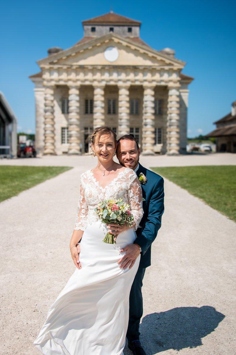 Mariés avec un bouquet devant les Salines d'Arc-et-Senans