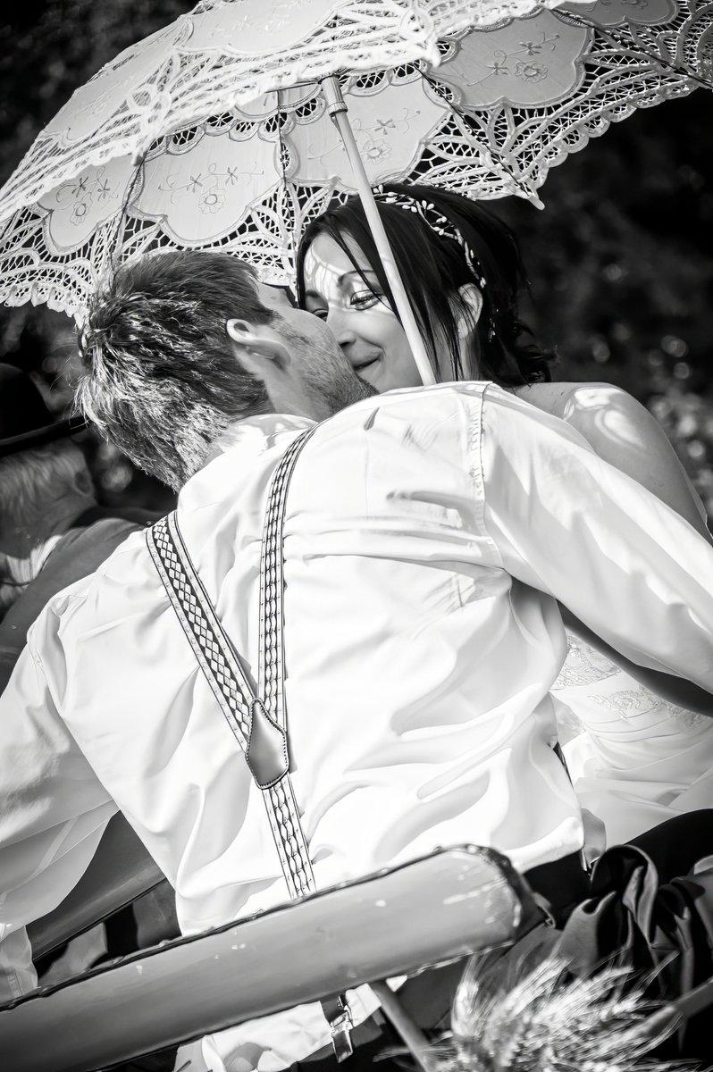 Mariés s'embrassant sous une ombrelle