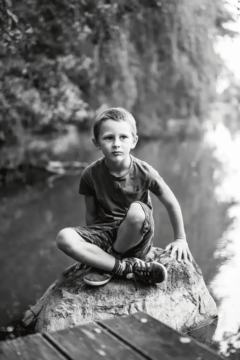 Enfant assis sur un rocher au bord de la rivière