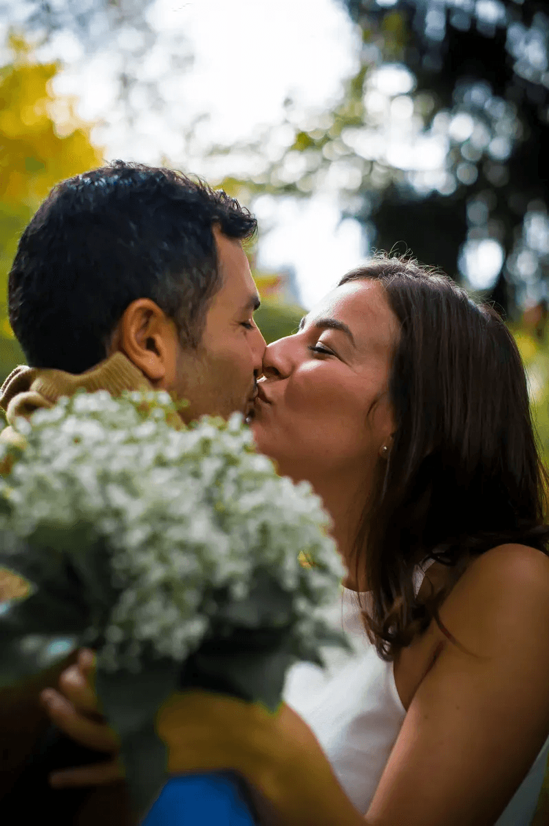 Futurs mariés qui s'embrassent avec un bouquet de fleurs