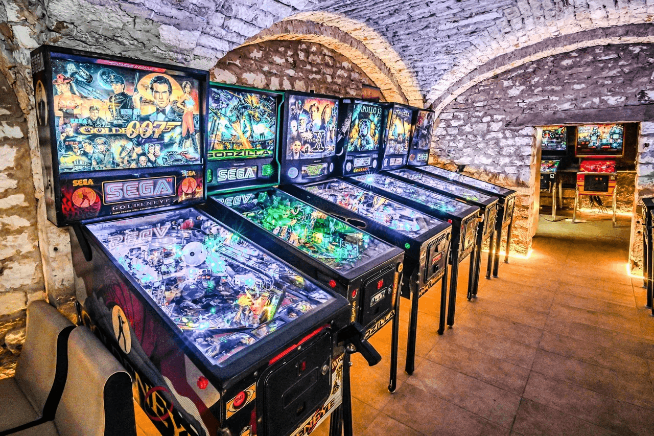 Cave voûtée en pierre aménagée en salle de jeux avec flippers