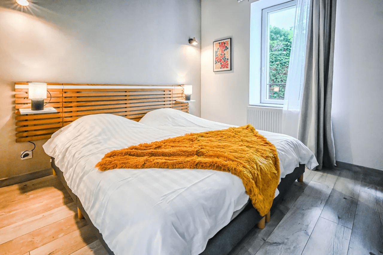Chambre avec lit double, plaid ocre et parquet — photo pour location