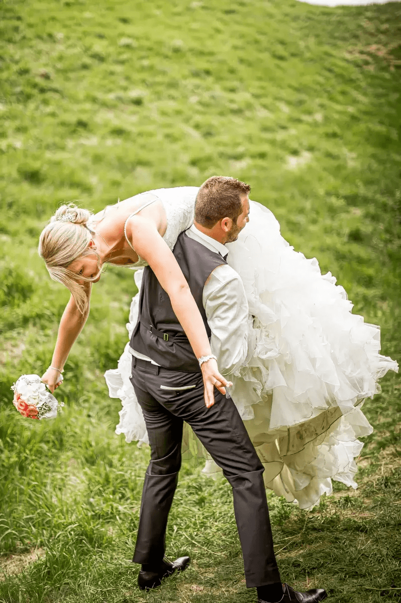 Marié portant la mariée sur son épaule dans l'herbe – Trash the Dress
