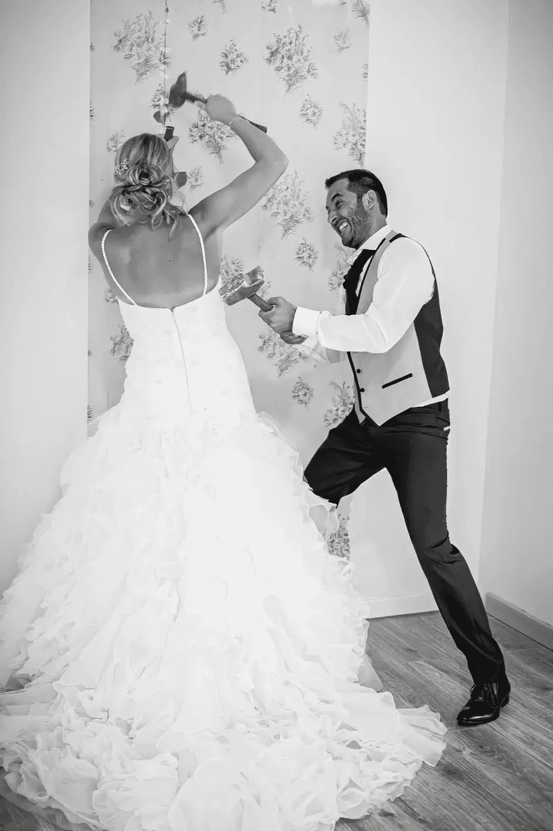 Mariés cassant un mur ensemble avec des marteaux – Trash the Dress