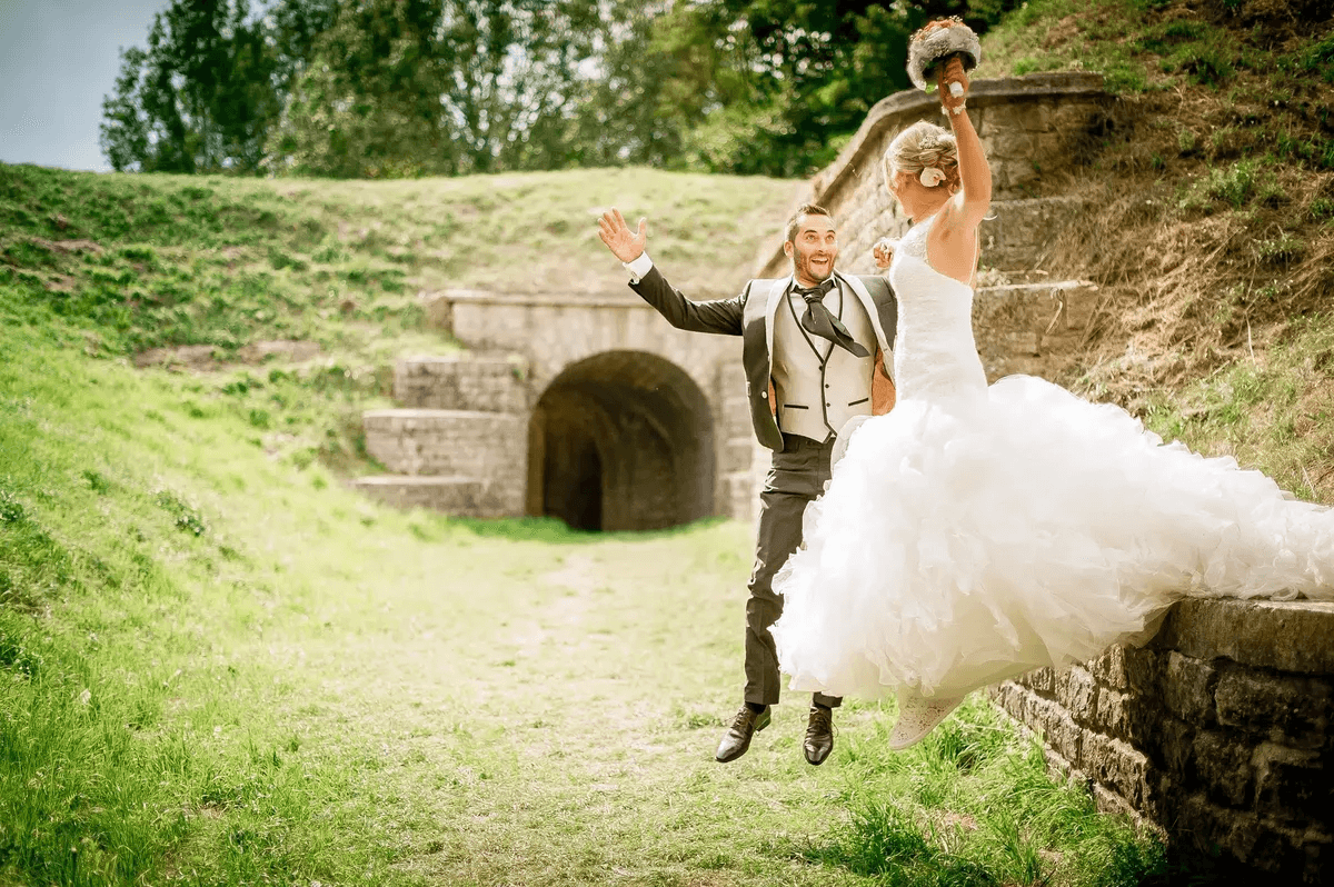 Mariés sautant ensemble devant une vieille structure en pierre – Trash the Dress